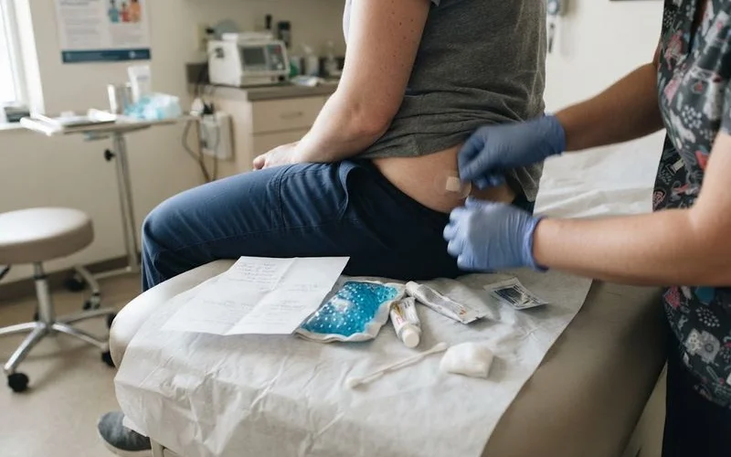 A close-up of a bandaged hormone pellet insertion site on a patient's hip after an in-office procedure